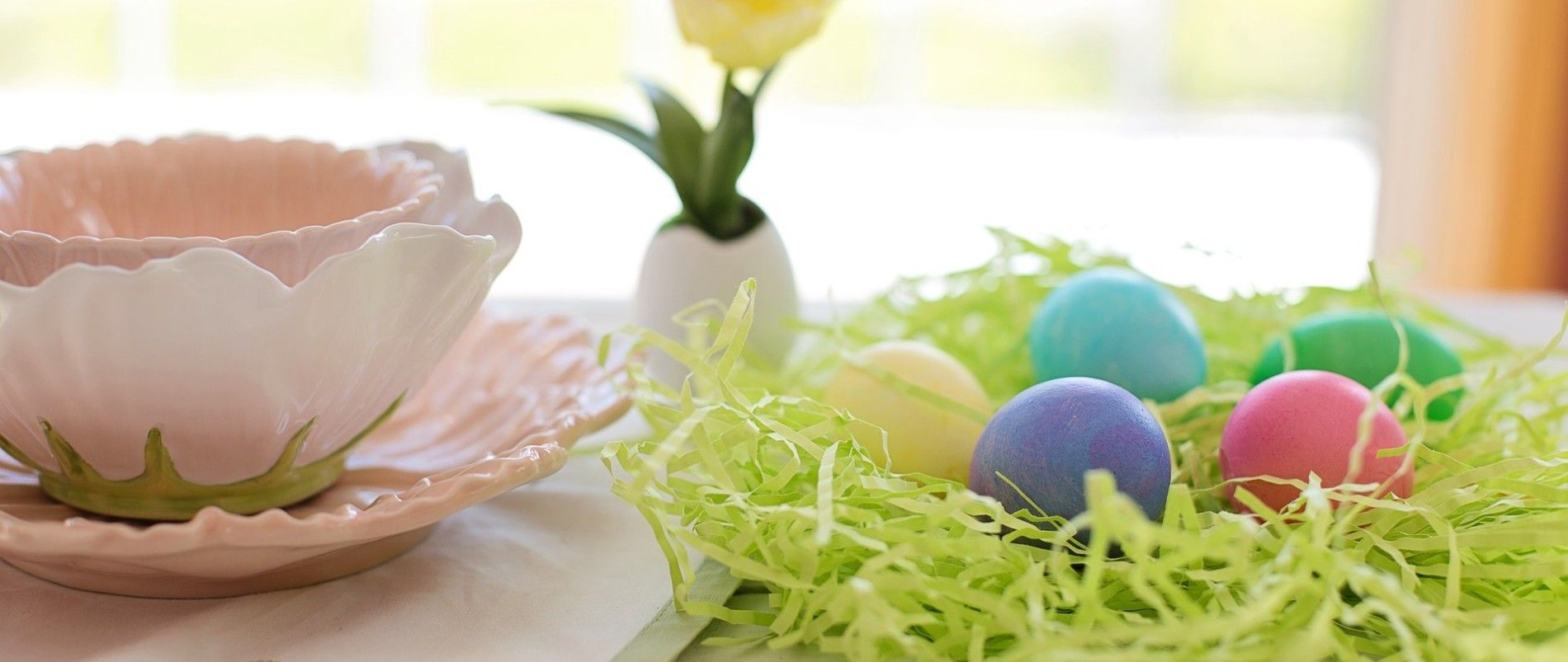 Osternest mit bunten Eiern und Blütengeschirr