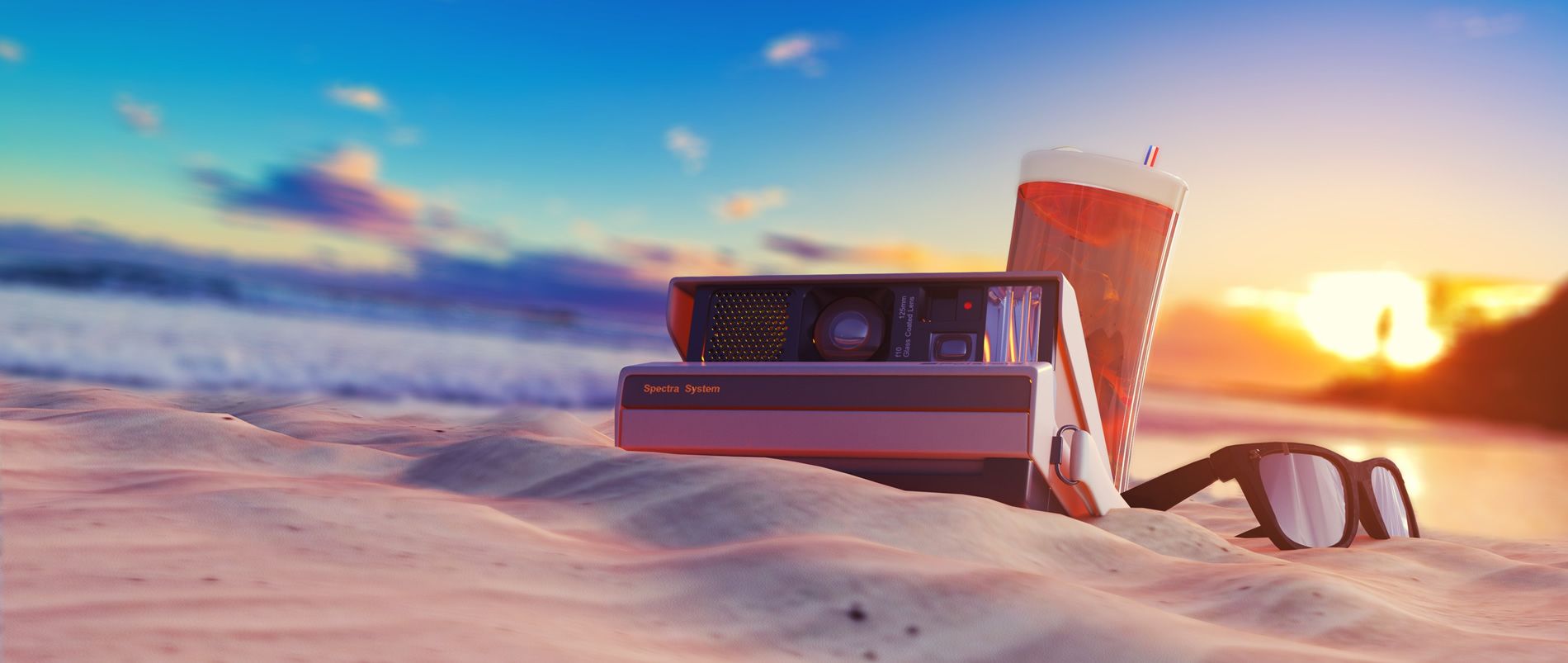 Strand mit Polaroid-Kamera, Sonnenbrille und einem Getränk bei Sonnenuntergang