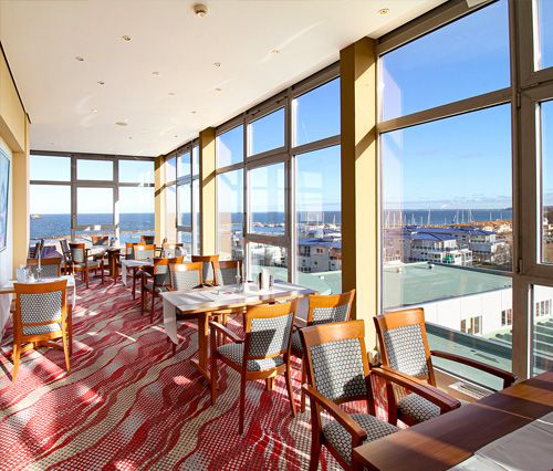 Helles Restaurant mit großen Fenstern und Blick auf das Meer.