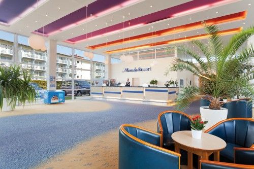 Heller Lobbybereich mit Empfangstresen, modernen Möbeln und exotischen Pflanzen.