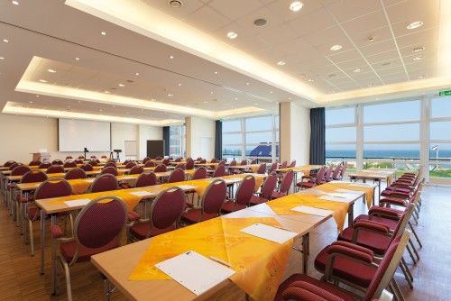 Großer Konferenzraum mit Tischen und Stühlen, Blick auf das Meer.