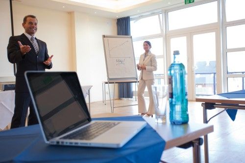 Präsentation in einem Konferenzraum mit zwei Personen, einem Laptop und einem Flipchart mit Diagramm
