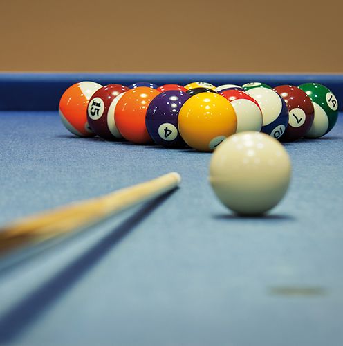 Billardtisch mit Billarkugeln und Queue.