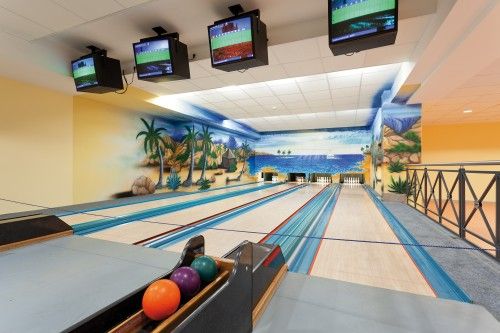 Eine Bowlingbahn mit drei Kugeln und Karibik-Wandmalerei im Hintergrund.