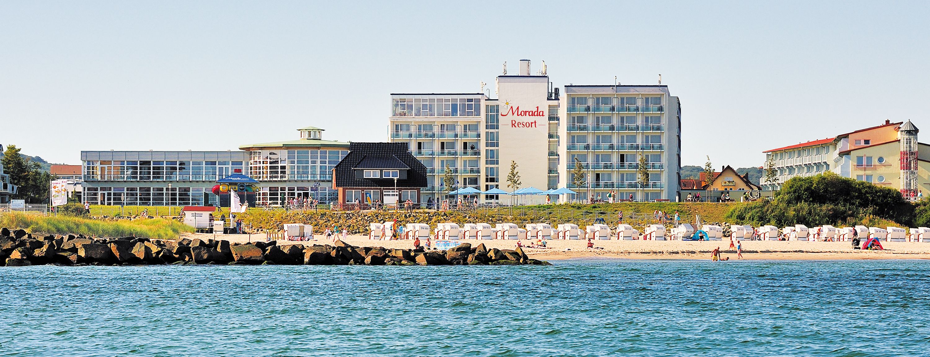 Hotelanlage am Strand mit Liegestühlen und Sonnenschirmen