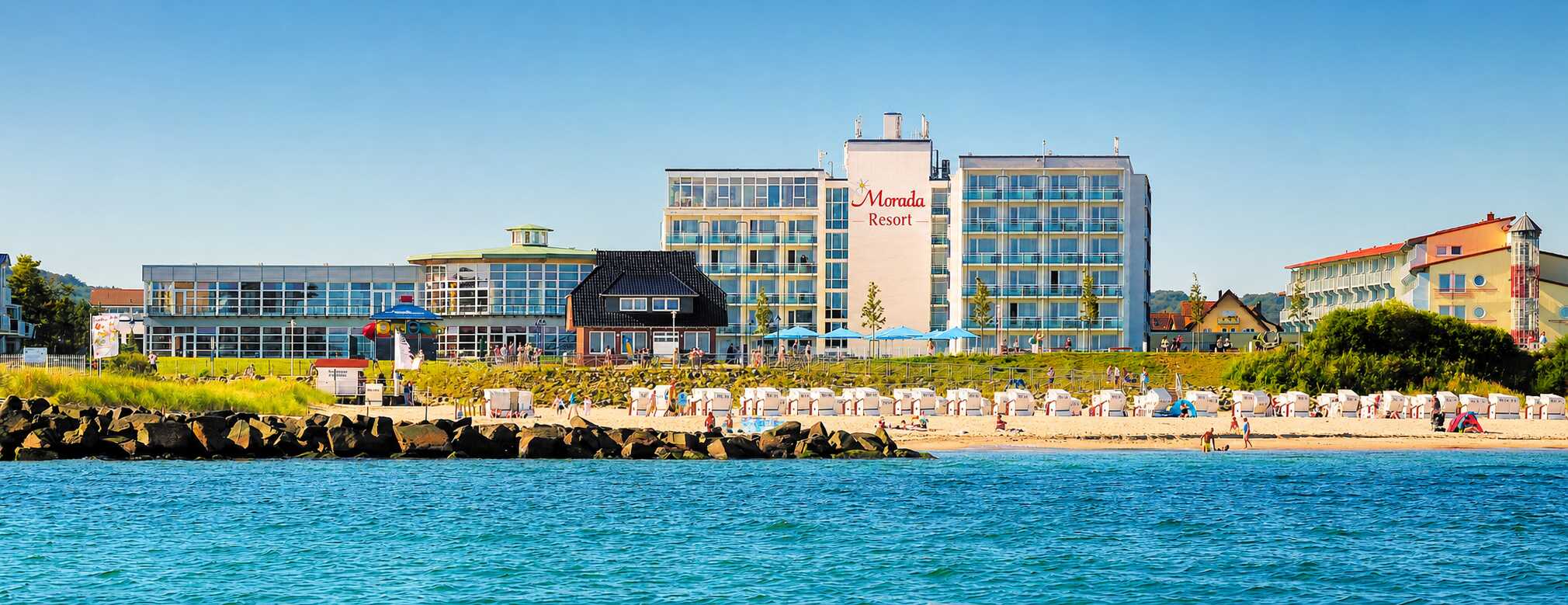 Hotelanlage am Strand mit Liegestühlen und Sonnenschirmen